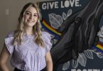 Tori Watson poses in front of a mural she painted